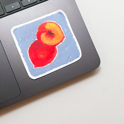Sticker of two peaches on a laptop trackpad
