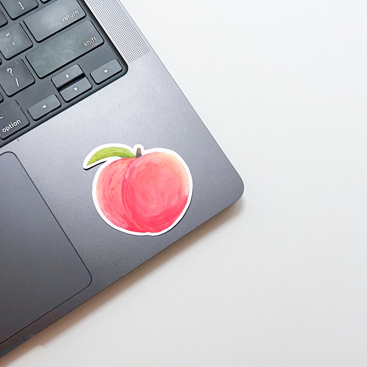 Laptop with a peach-shaped sticker on the palm rest area
