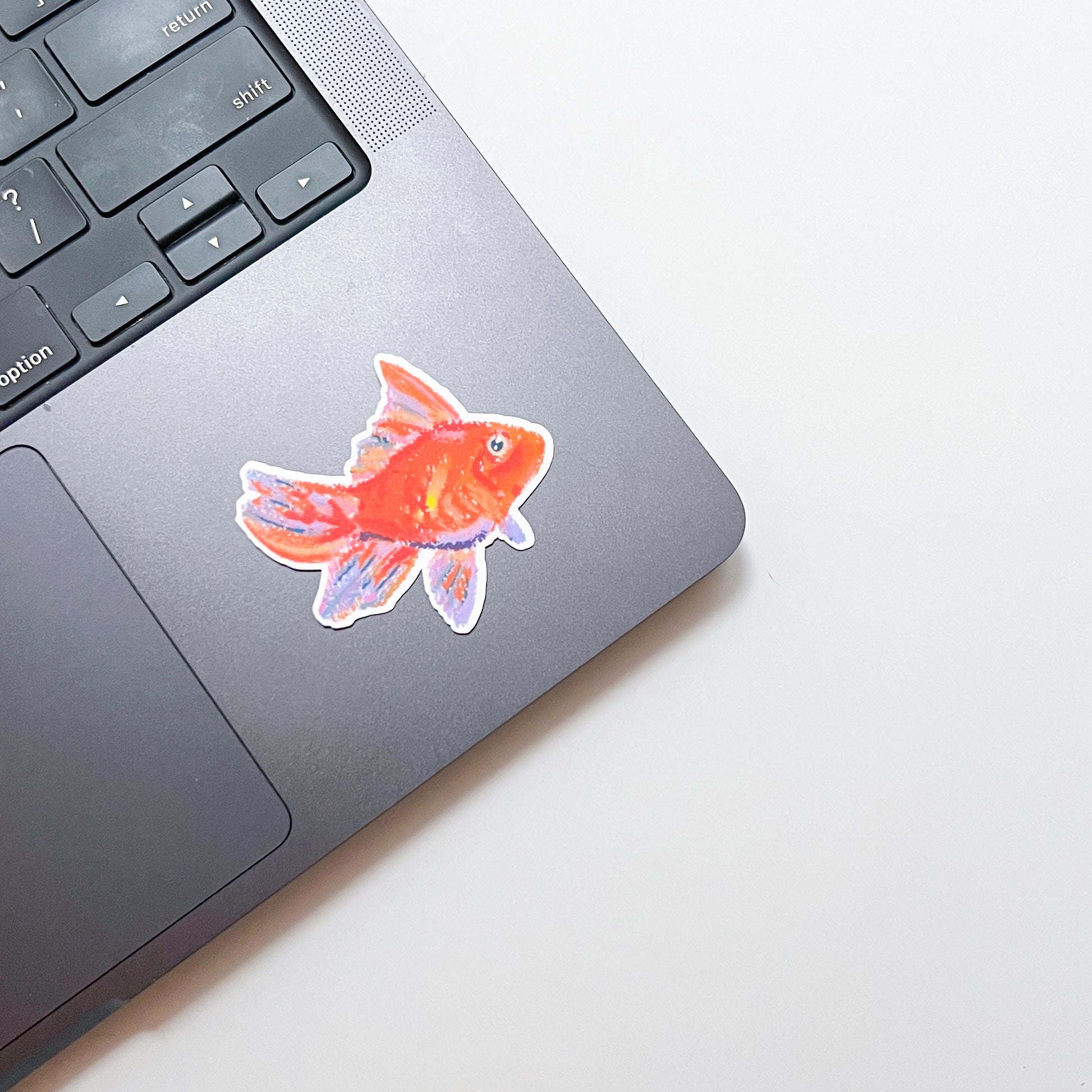 Laptop with a goldfish sticker on a light background