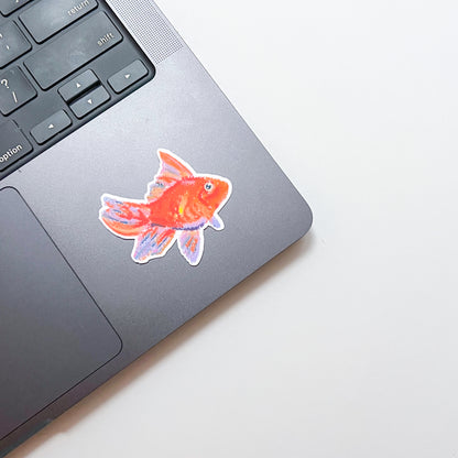Laptop with a goldfish sticker on a light background