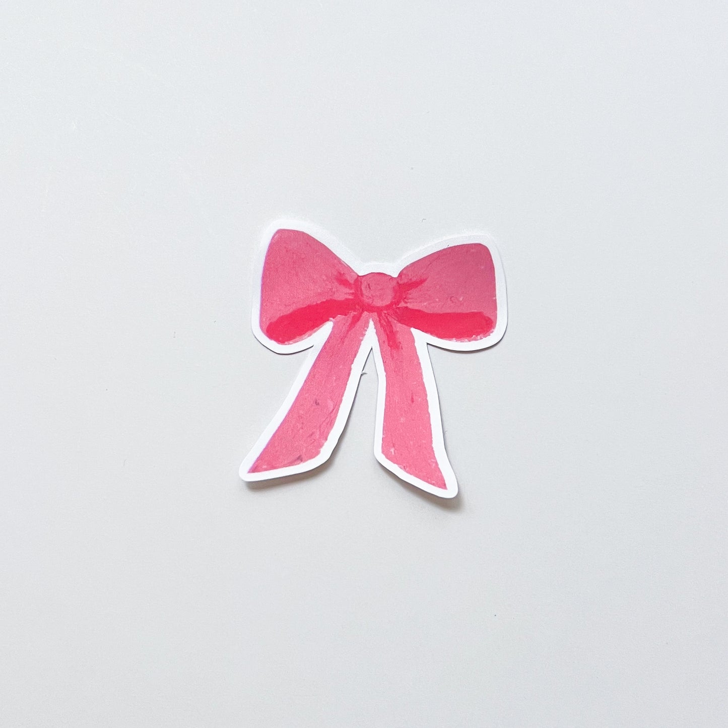 Pink bow-shaped sticker on a light gray background