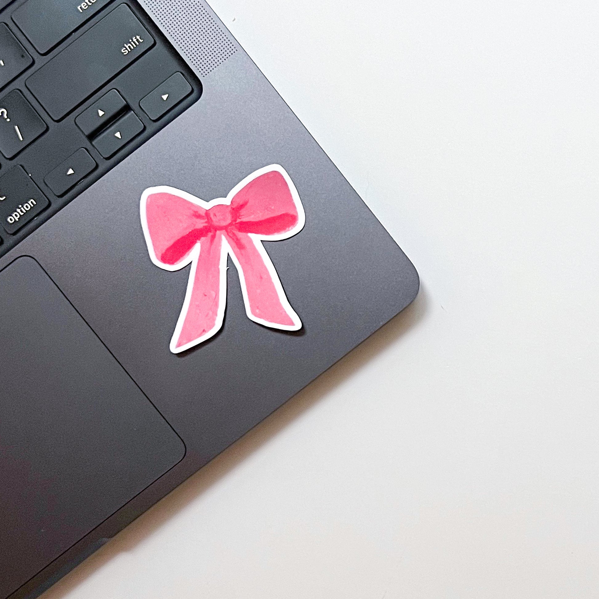Pink bow sticker on a laptop keyboard