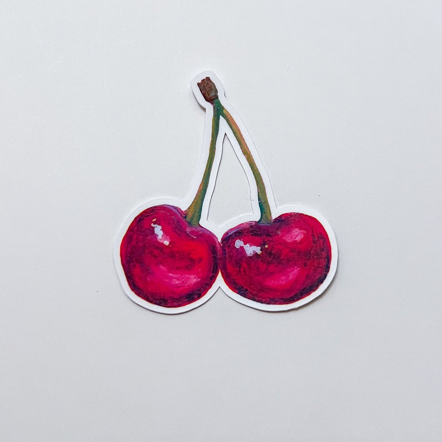 Sticker of two red cherries on a light gray background