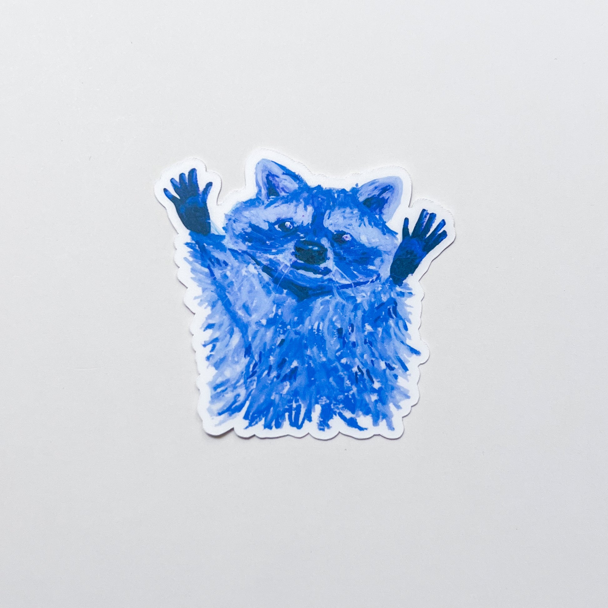 Blue raccoon sticker on a light gray background