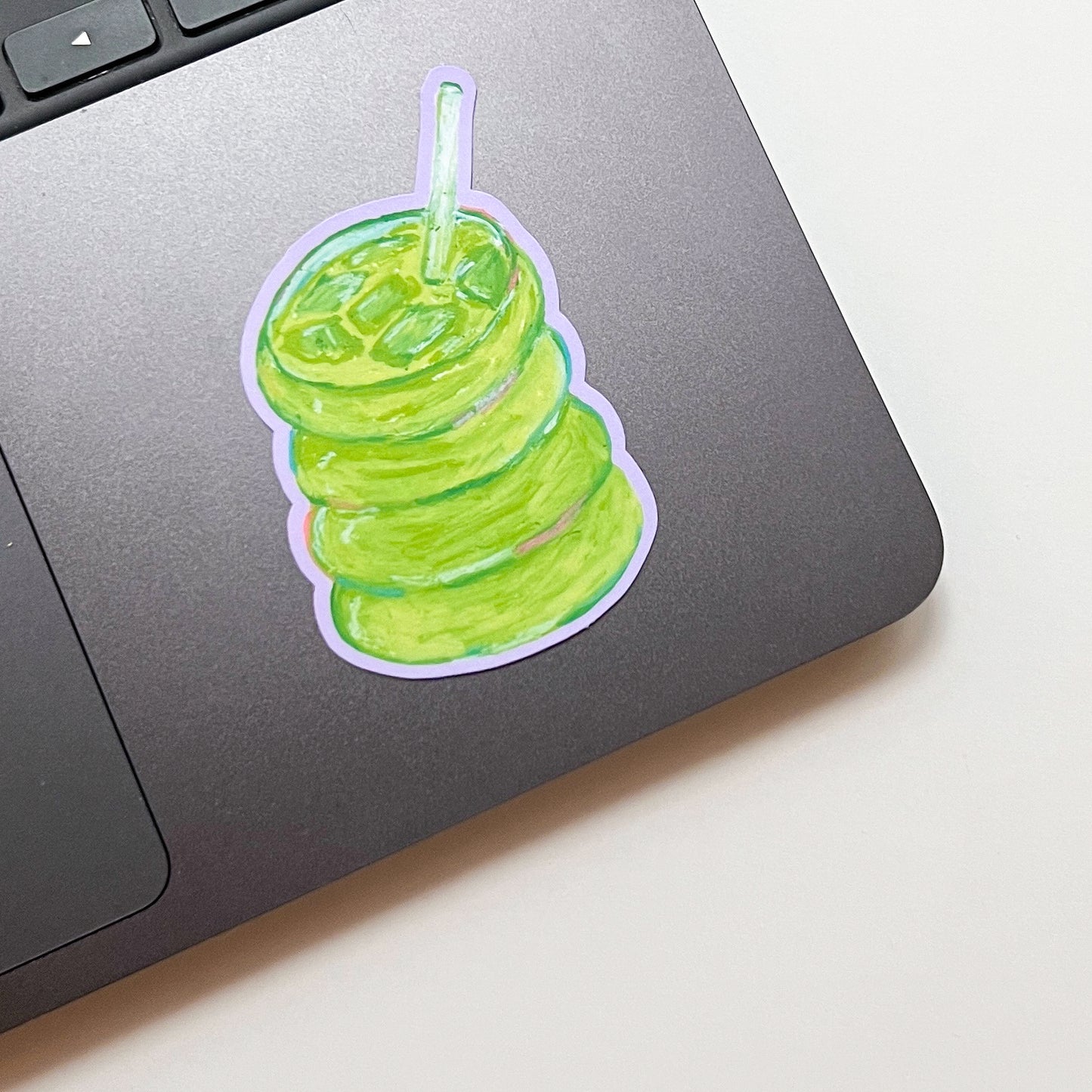 Laptop with a green drink sticker on a light surface