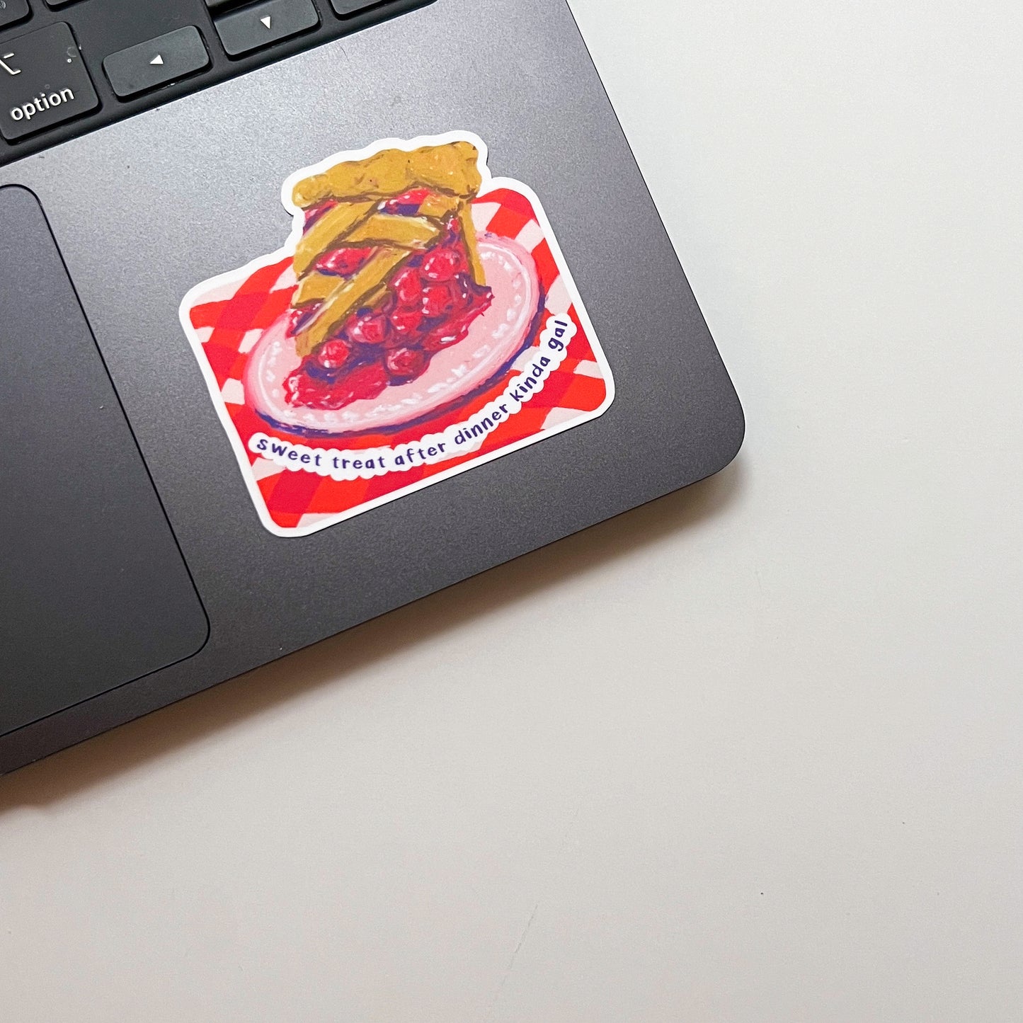 Laptop with a pie-themed sticker on a light surface