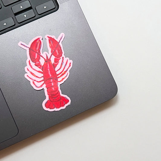 Laptop with a red lobster sticker on a light surface