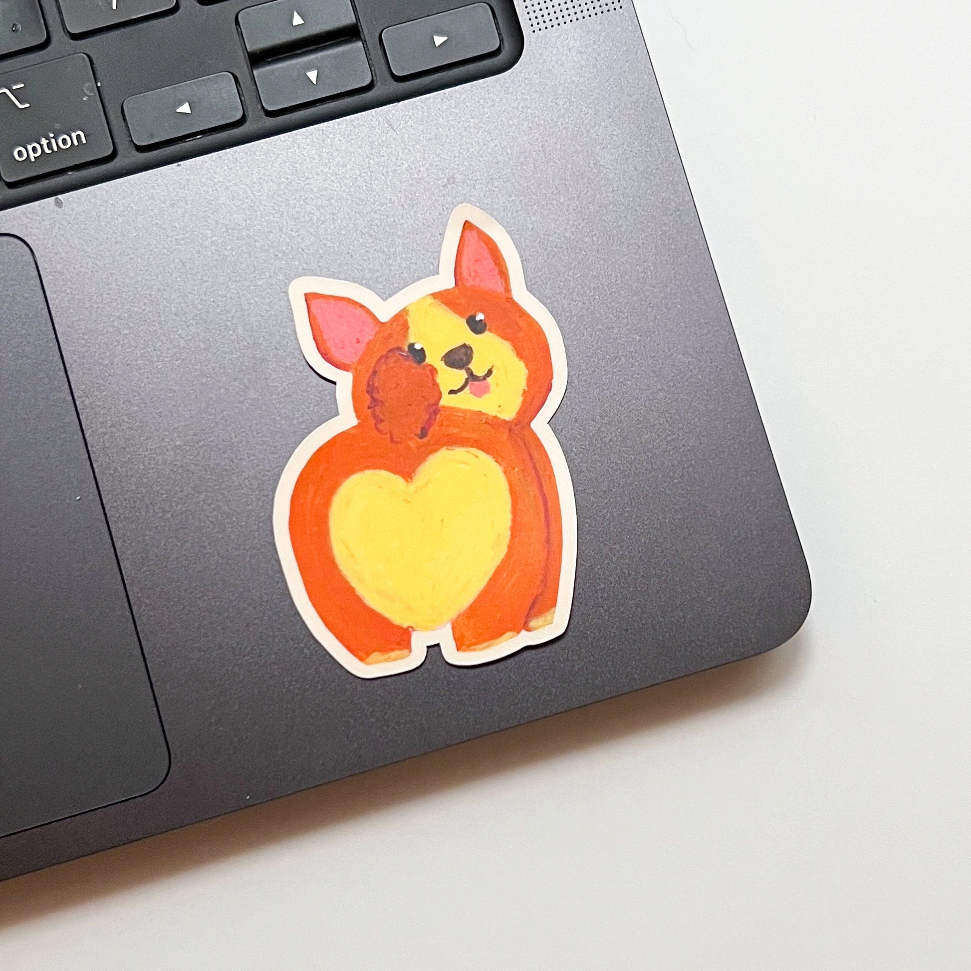 Laptop with a cute dog sticker featuring a heart on a light background