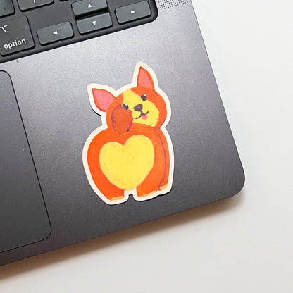 Laptop with a cute dog sticker featuring a heart on a light background