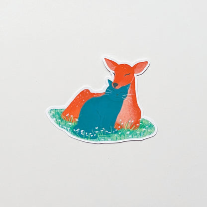 Sticker of a deer and cat sitting on grass with a light grey background