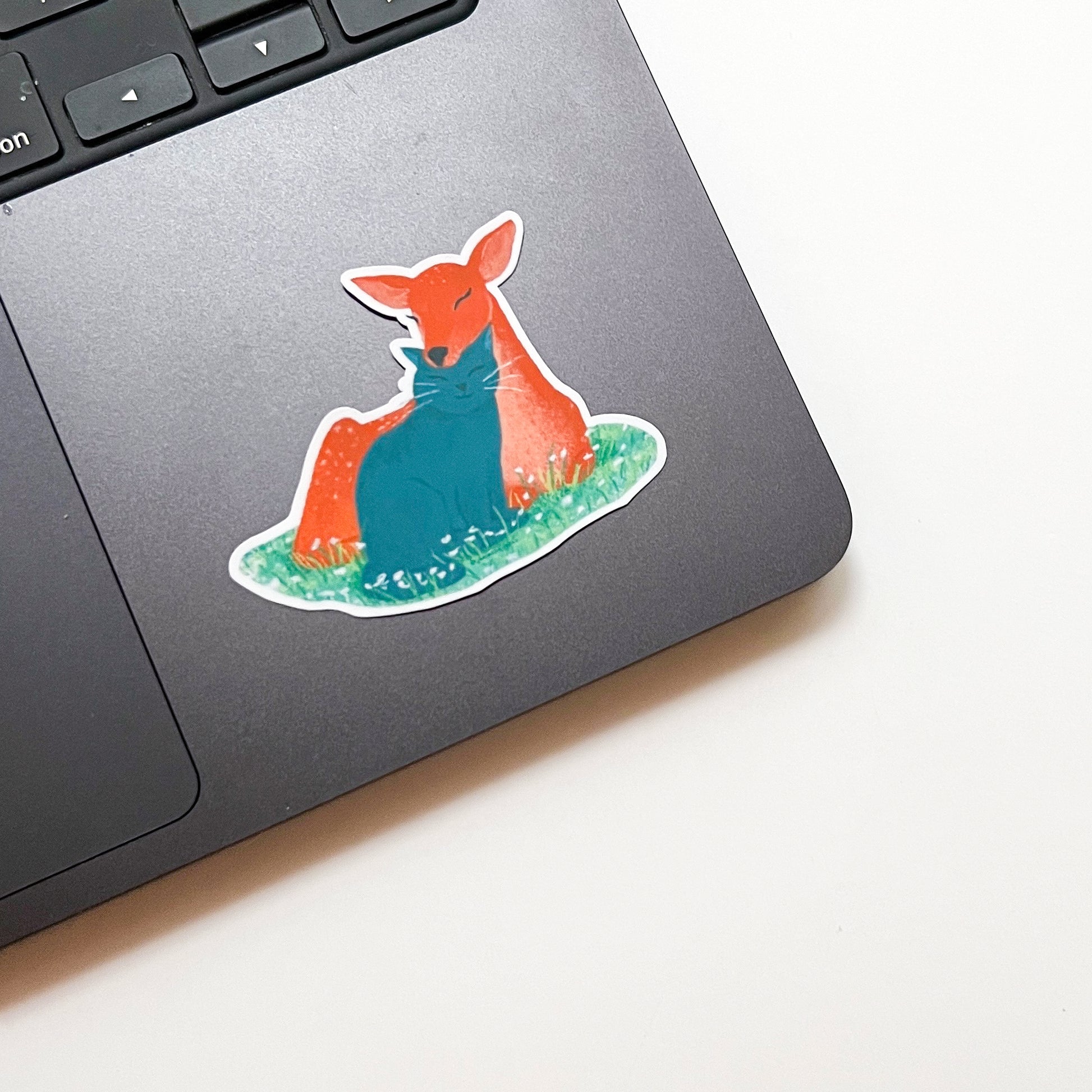 Laptop with a colorful deer sticker on a white surface