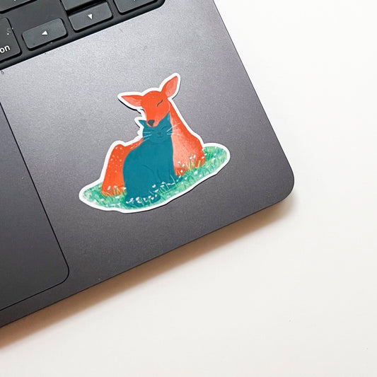 Laptop with a colorful deer sticker on a white surface