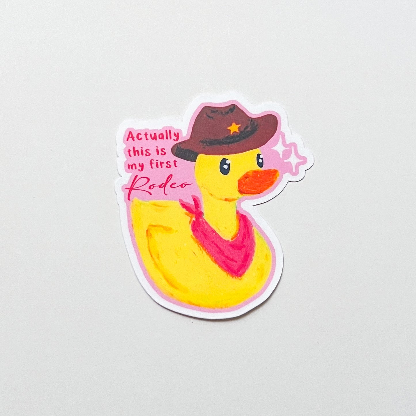 Sticker of a rubber duck wearing a cowboy hat and bandana with text on a light gray background