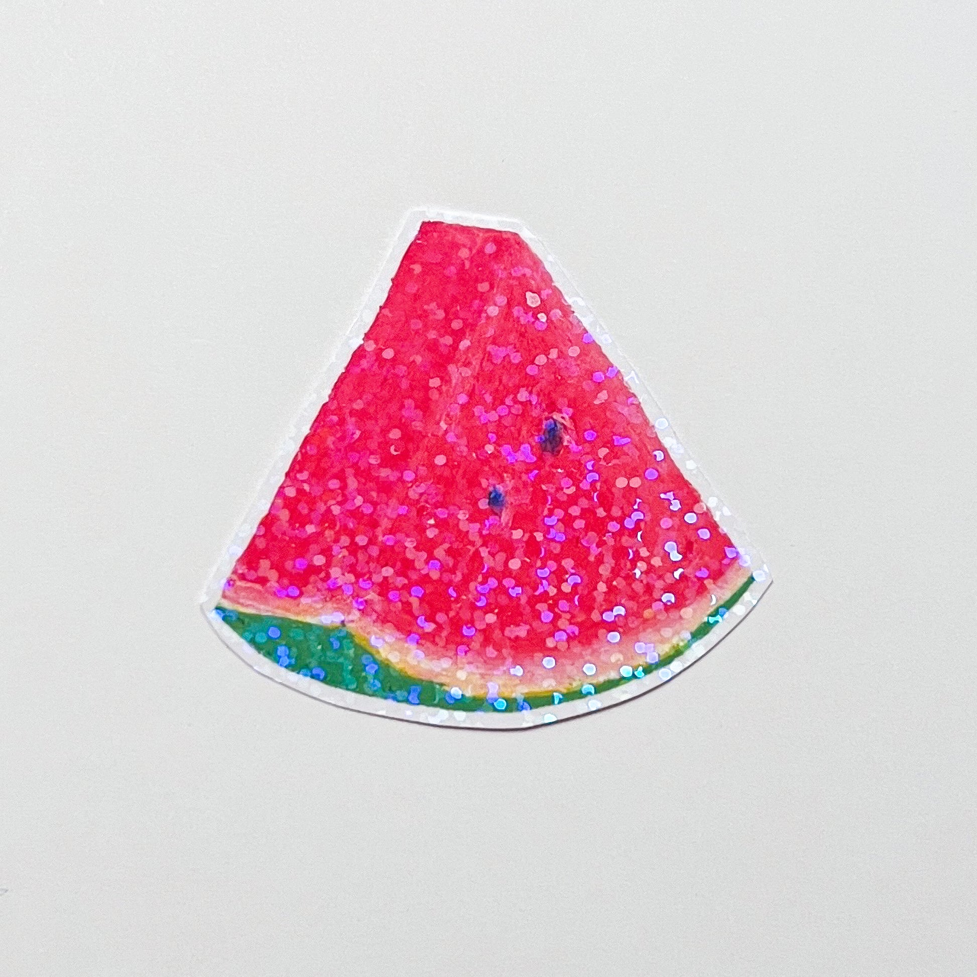 Watermelon slice with pink glitter on a light gray background