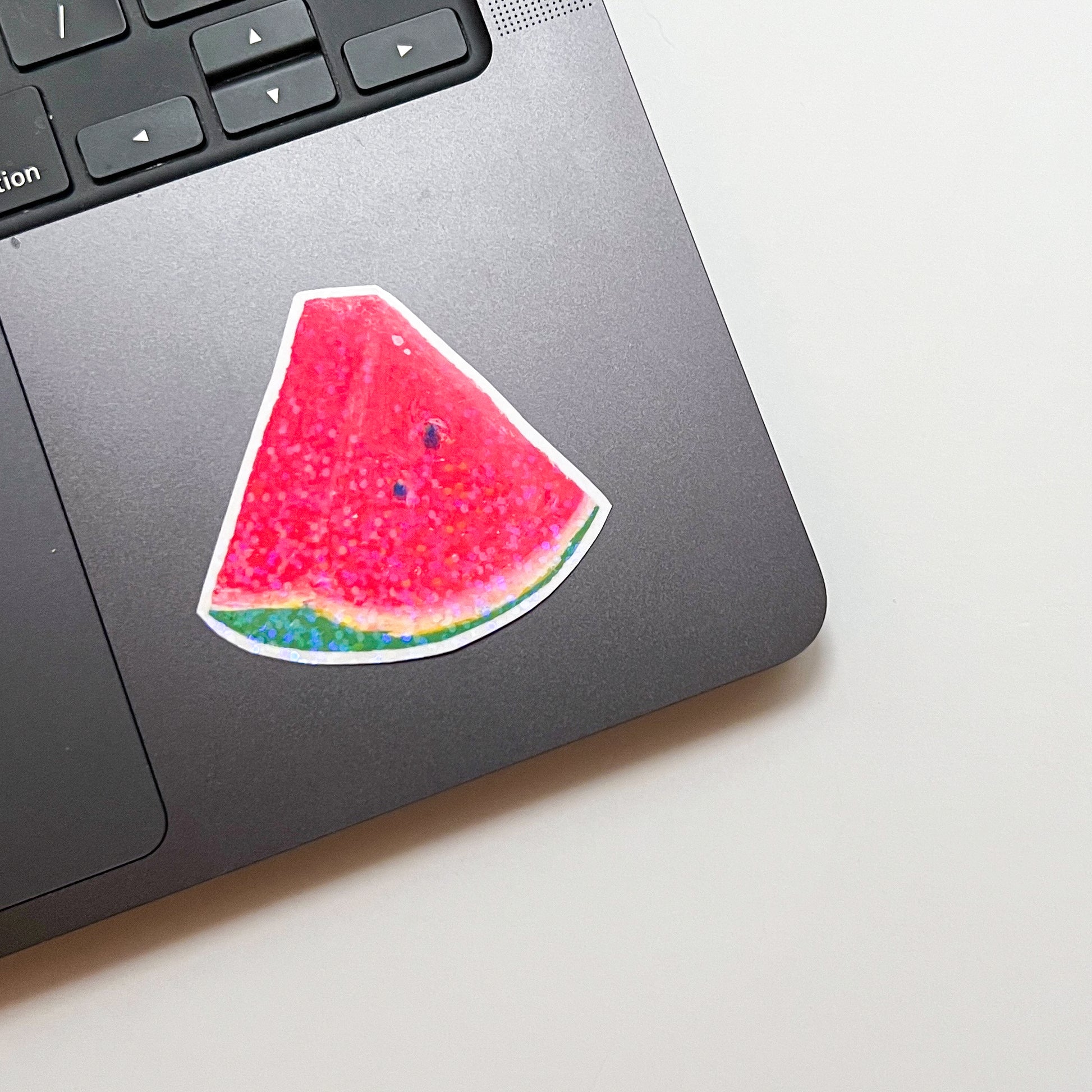 Laptop with a watermelon slice sticker on a light surface