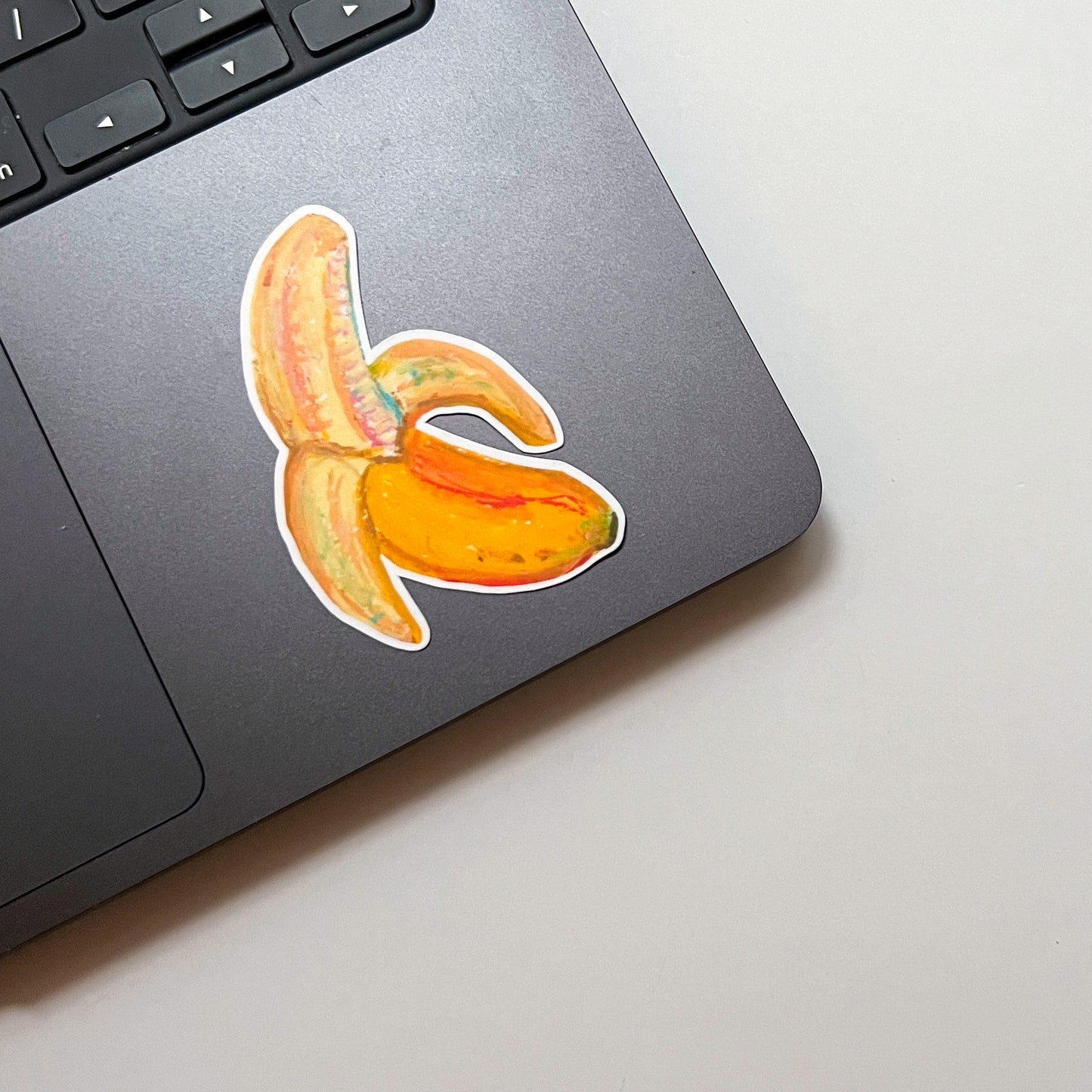 Laptop with a banana peel sticker on a light surface