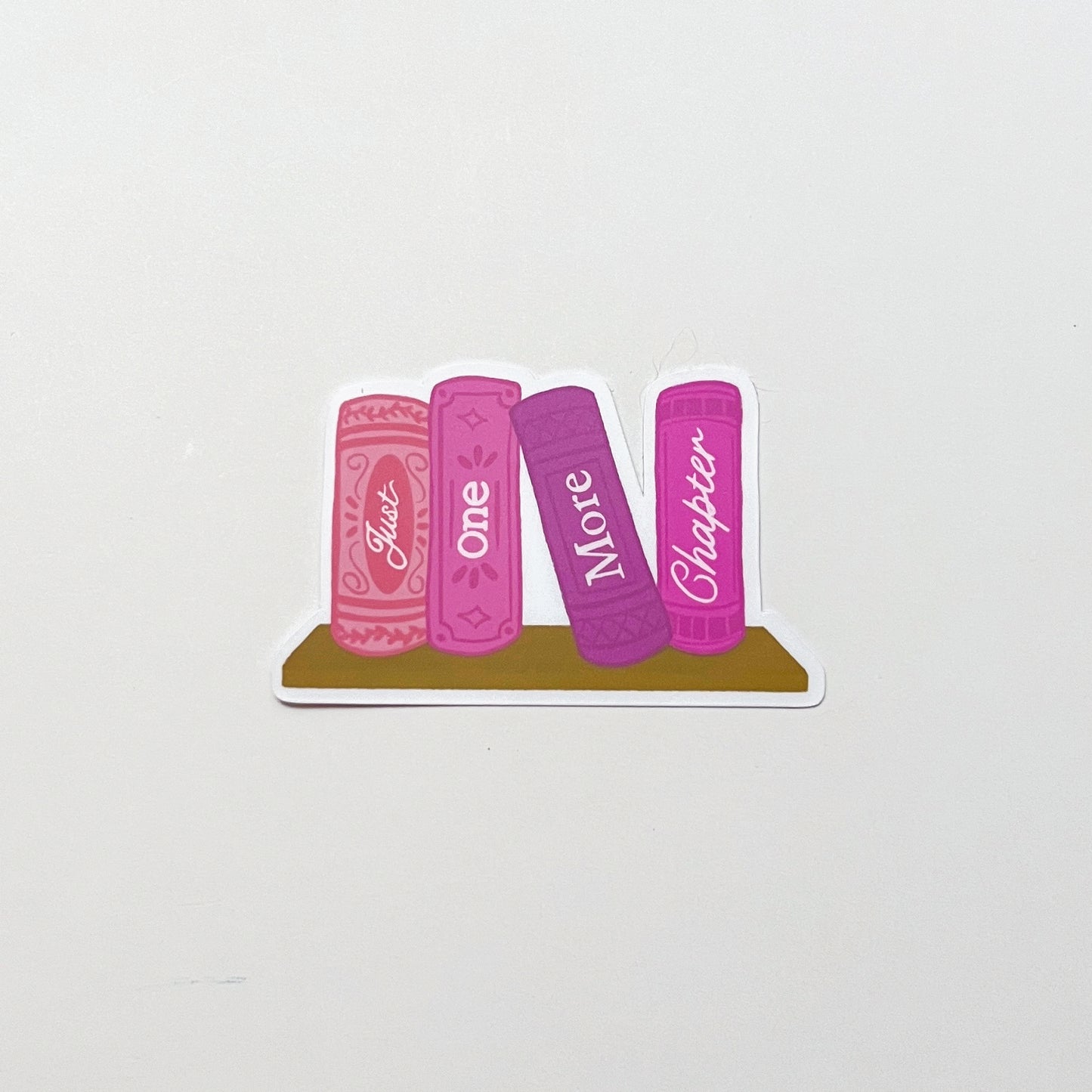 Sticker design of four pink books with text 'just one more chapter' on a white background