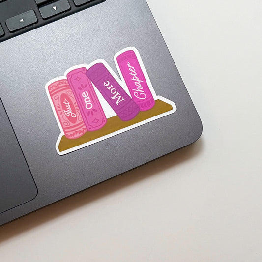 Laptop with a decorative sticker of pink books on a light surface
