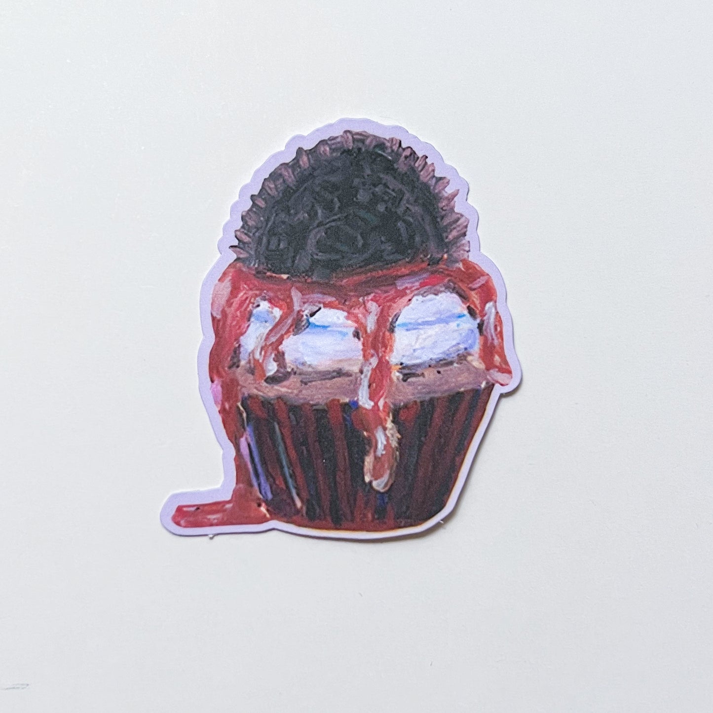 Sticker of a cupcake with a black top and red frosting on a light gray background