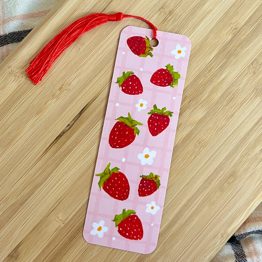 Pink bookmark with strawberry design on a wooden surface