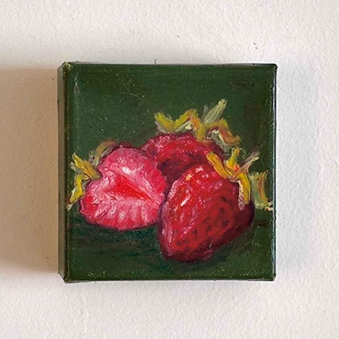 Small painting of strawberries on a green background