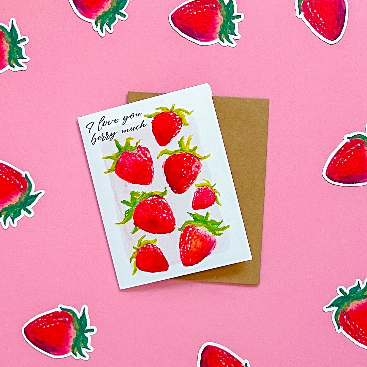 Greeting card with strawberry design and 'I love you berry much' text on a pink background with strawberry stickers.