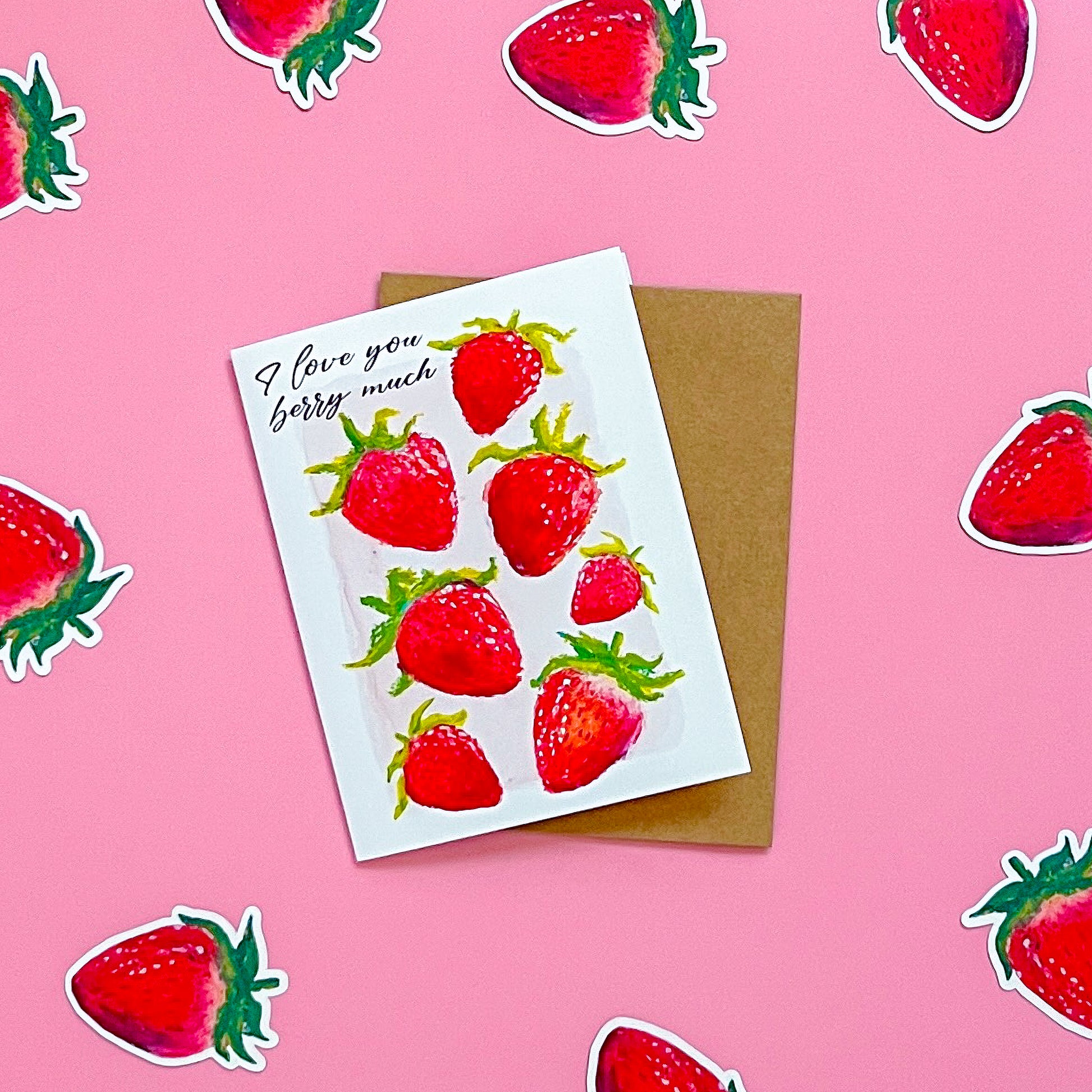 Greeting card with strawberry design and 'I love you berry much' text on a pink background with strawberry stickers.