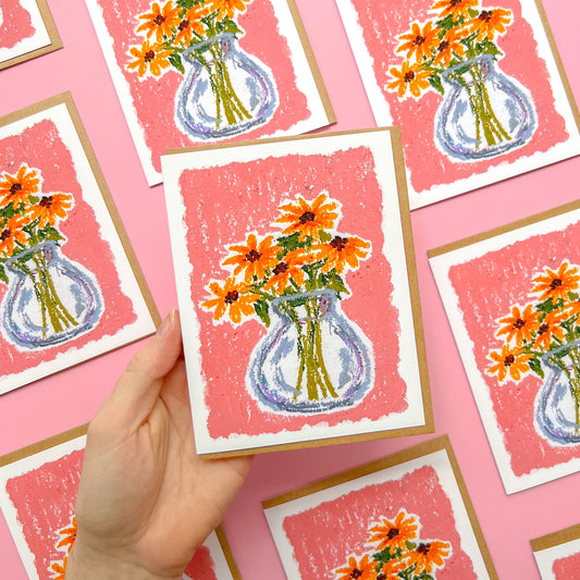 hand holding a greeting card with an oil pastel drawing of a flower vase