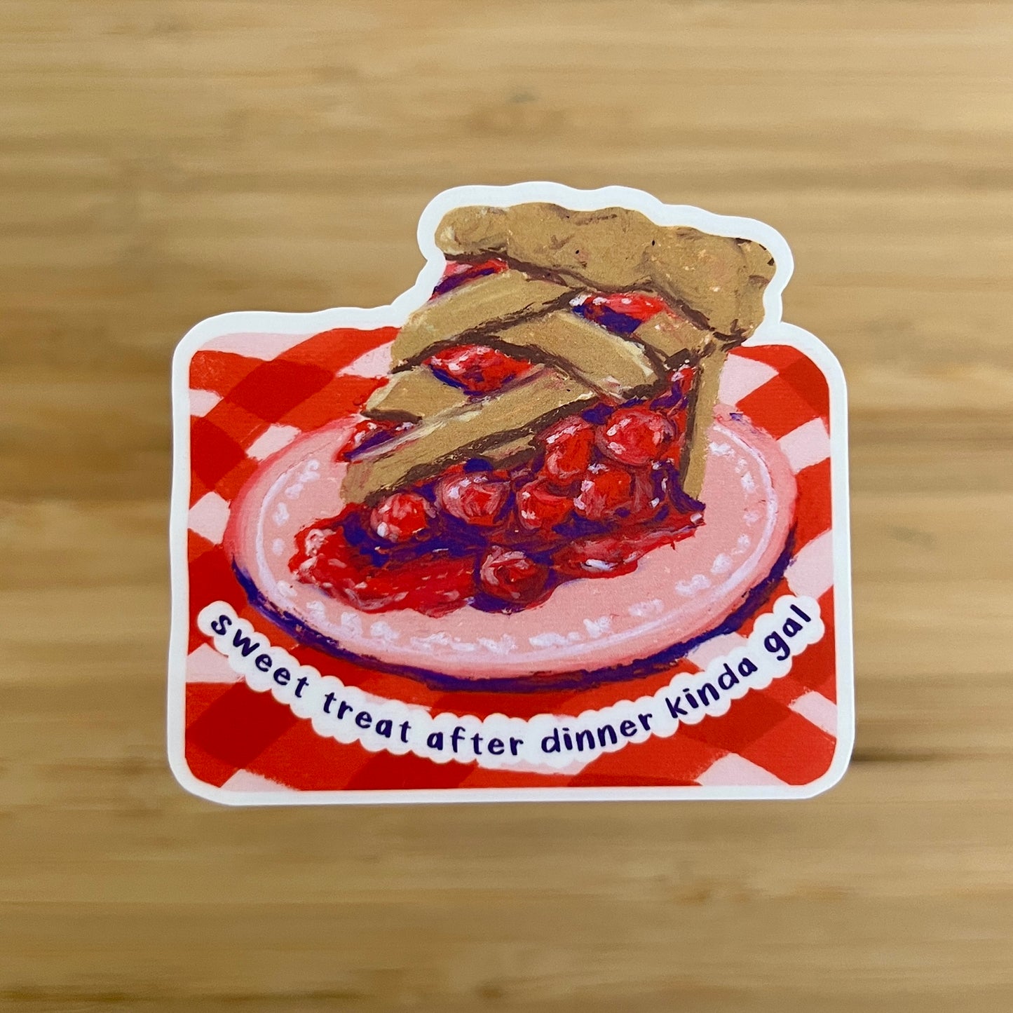 Sticker of a slice of cherry pie on a red and white checkered tablecloth with text 'sweet treat after dinner kinda gal"