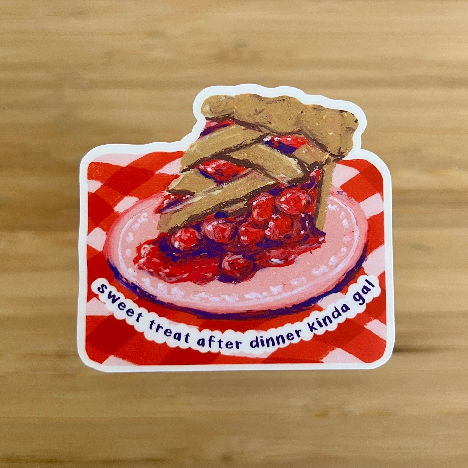 Sticker of a slice of cherry pie on a red and white checkered tablecloth with text 'sweet treat after dinner kinda gal"