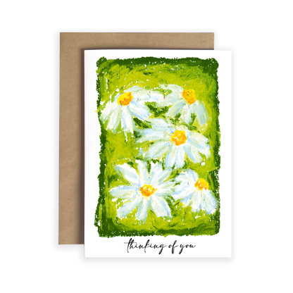 Greeting card with daisy flowers and 'thinking of you' text on a green background