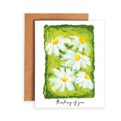 Greeting card with daisy flowers and 'thinking of you' text on a green background
