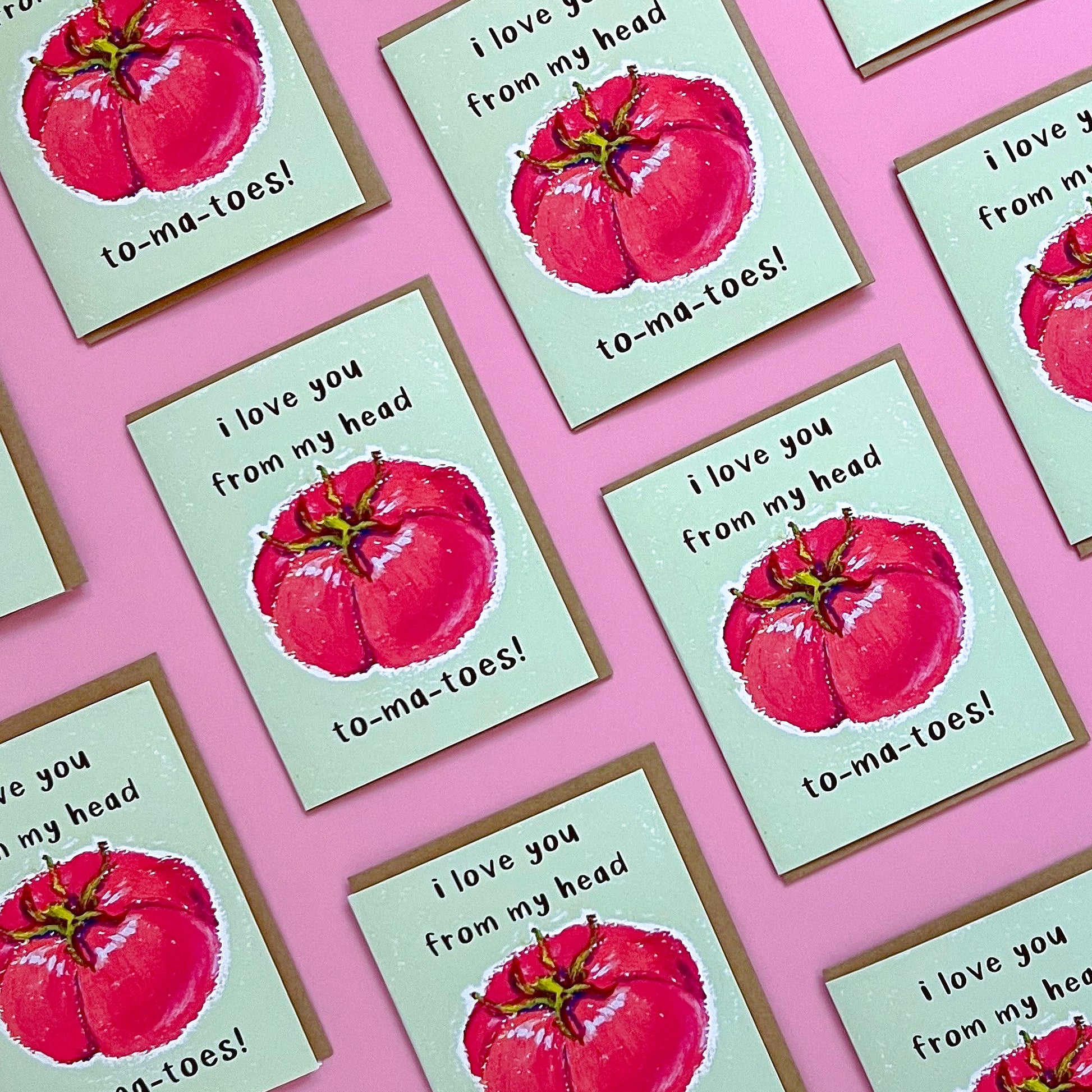 Greeting card with red tomato illustration and text 'I love you from my head tomatoes' on a pink background