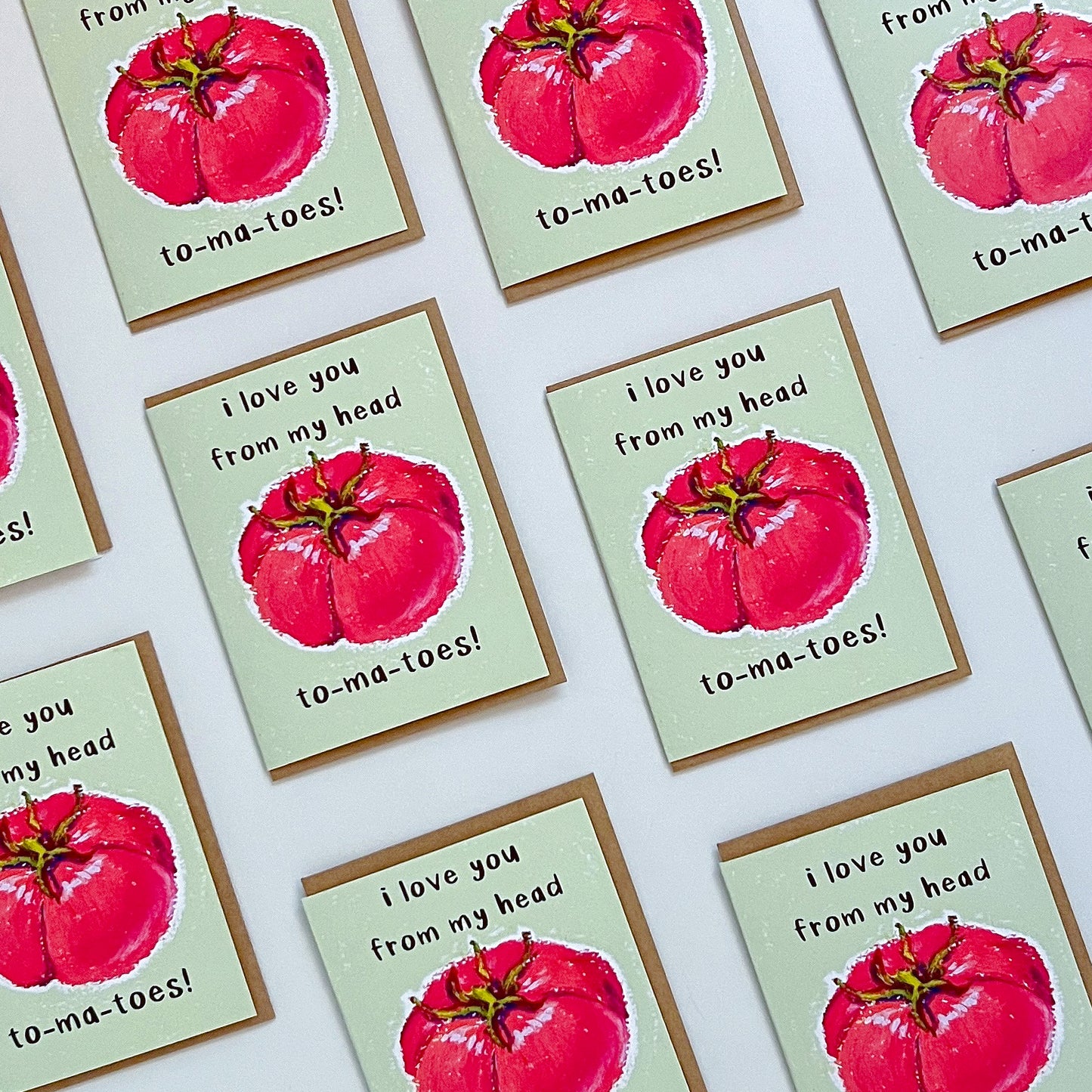 Greeting card with red tomato illustration and text 'I love you from my head tomatoes' on a white background