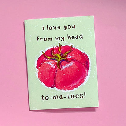 Greeting card with red tomato illustration and text 'I love you from my head tomatoes' on a pink background