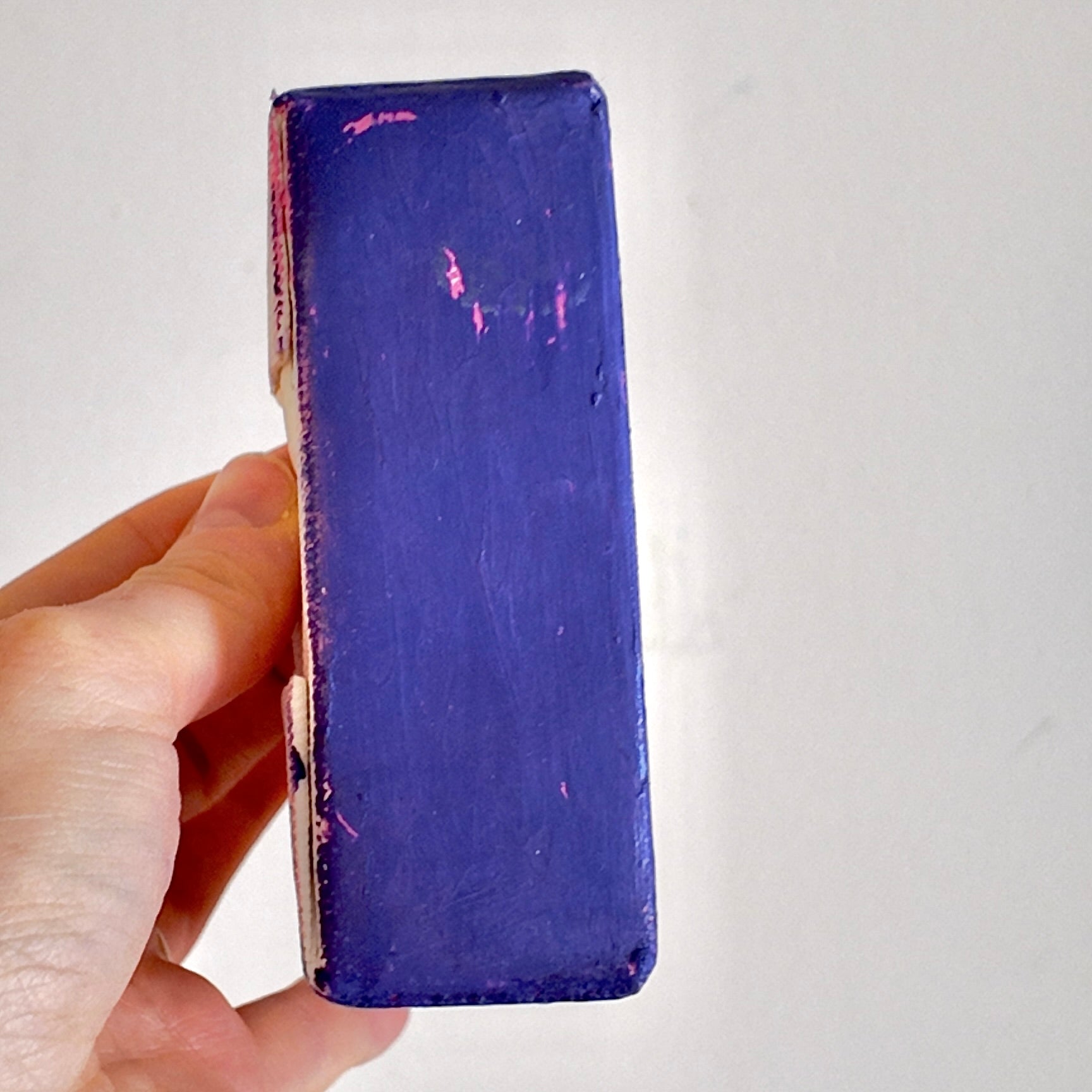 Hand holding a purple canvas on side profile against a white background