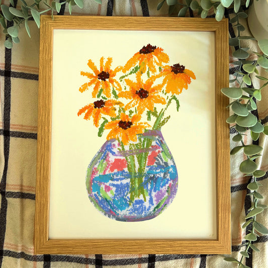 Framed cross-stitched artwork of a vase with flowers on a checkered fabric background